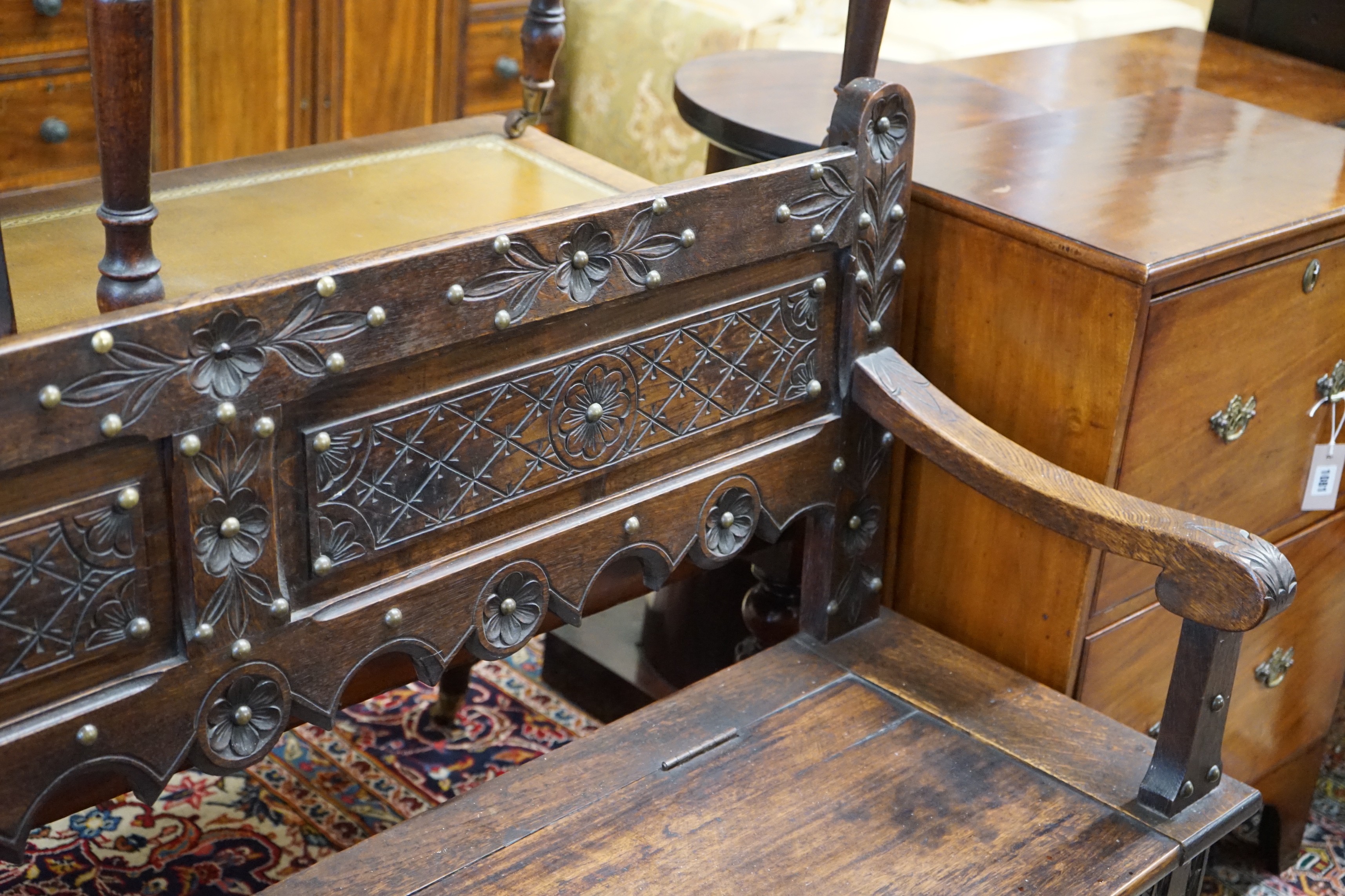 An 18th century style brass studded carved oak box seat settle, length 136cm, depth 40cm, height 93cm